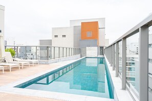 A rooftop swimming pool with a modern design, surrounded by lounge chairs and a glass balustrade. - Charlie Edição Jardim Paulista (São Paulo)