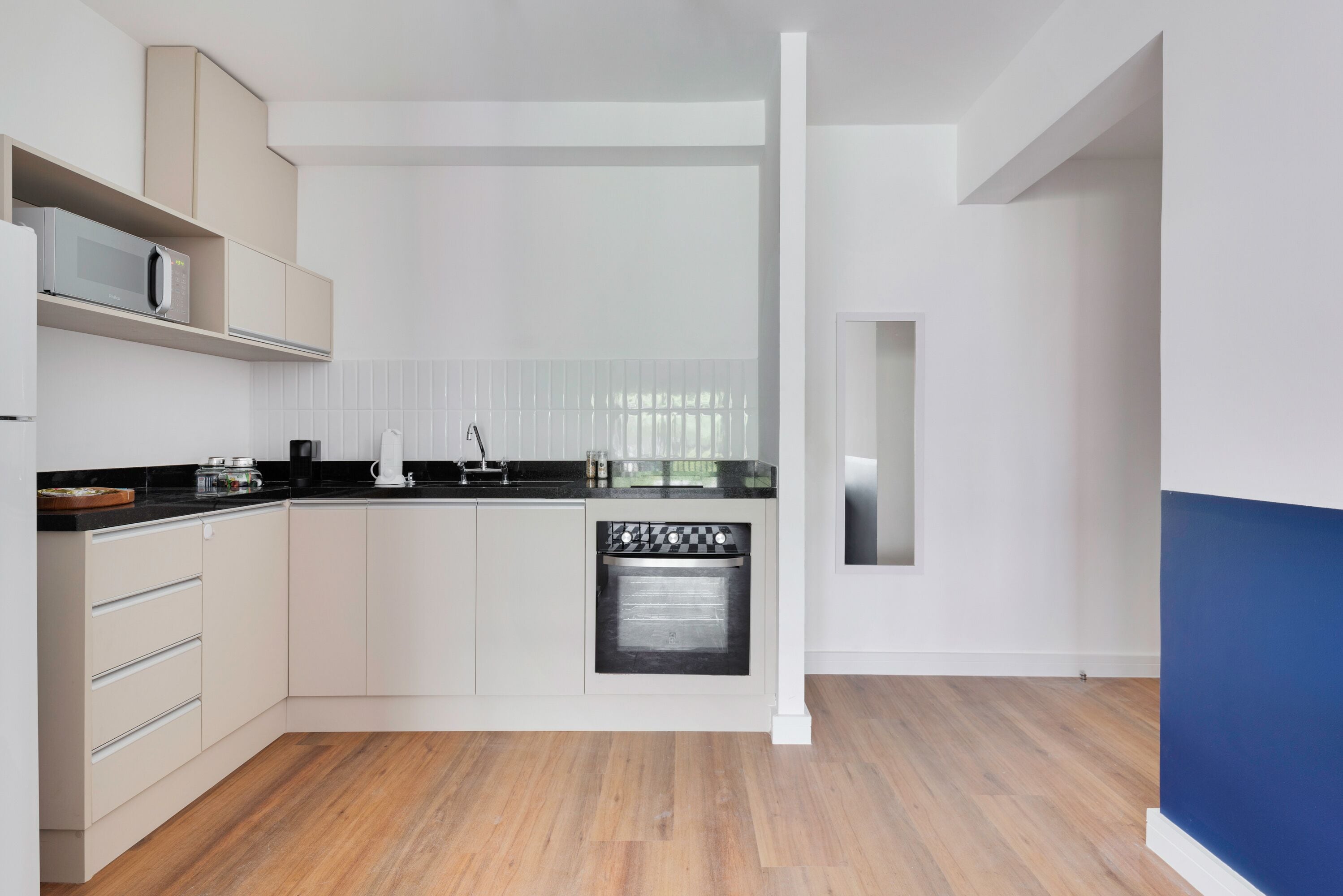 A modern kitchen with white cabinetry, a black countertop, and a built-in dishwasher.