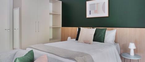 Une chambre à coucher moderne avec un lit, une table de chevet, une armoire et un tableau encadré au mur.