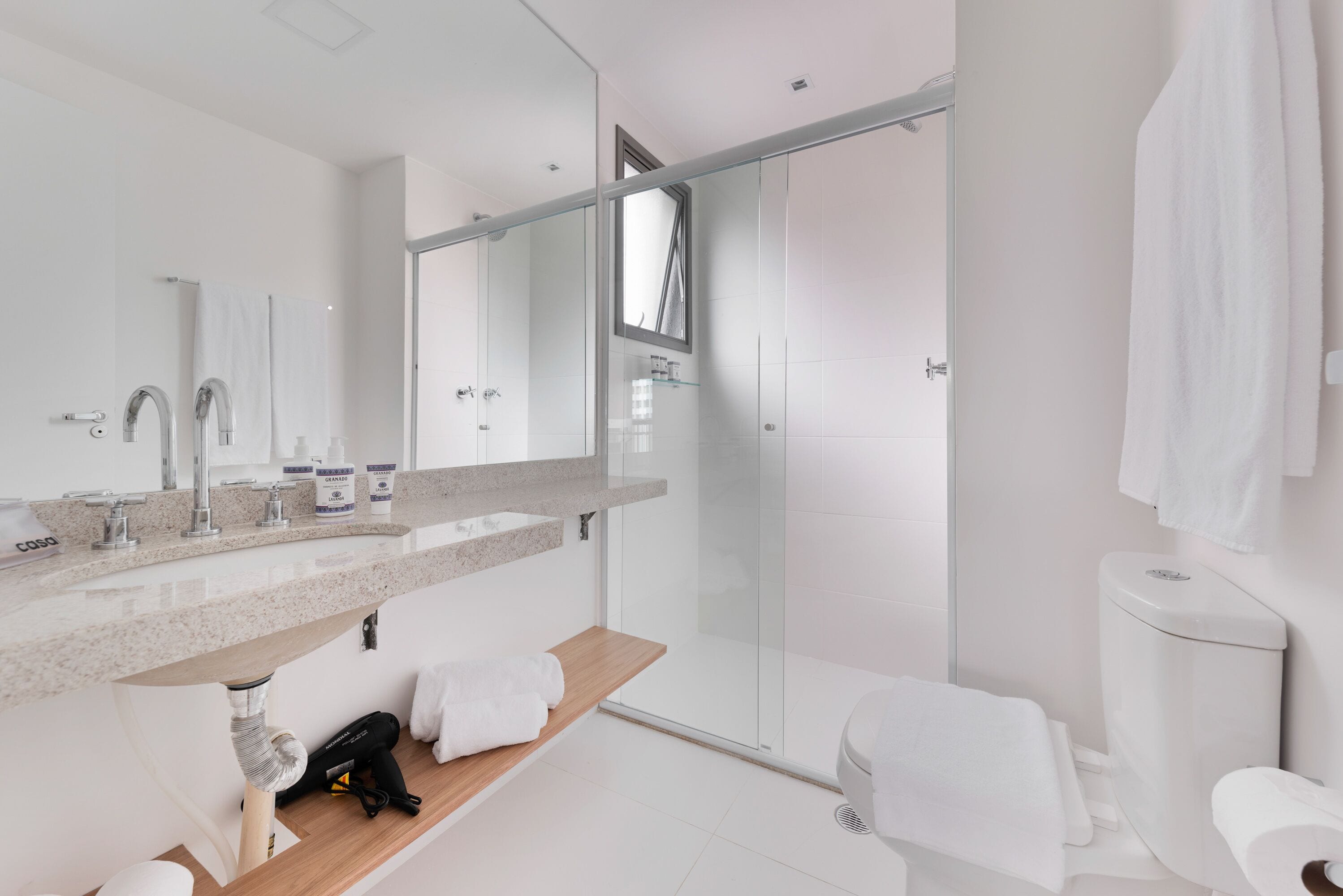A modern bathroom with a glass-enclosed shower, a large mirror, and a wooden vanity.