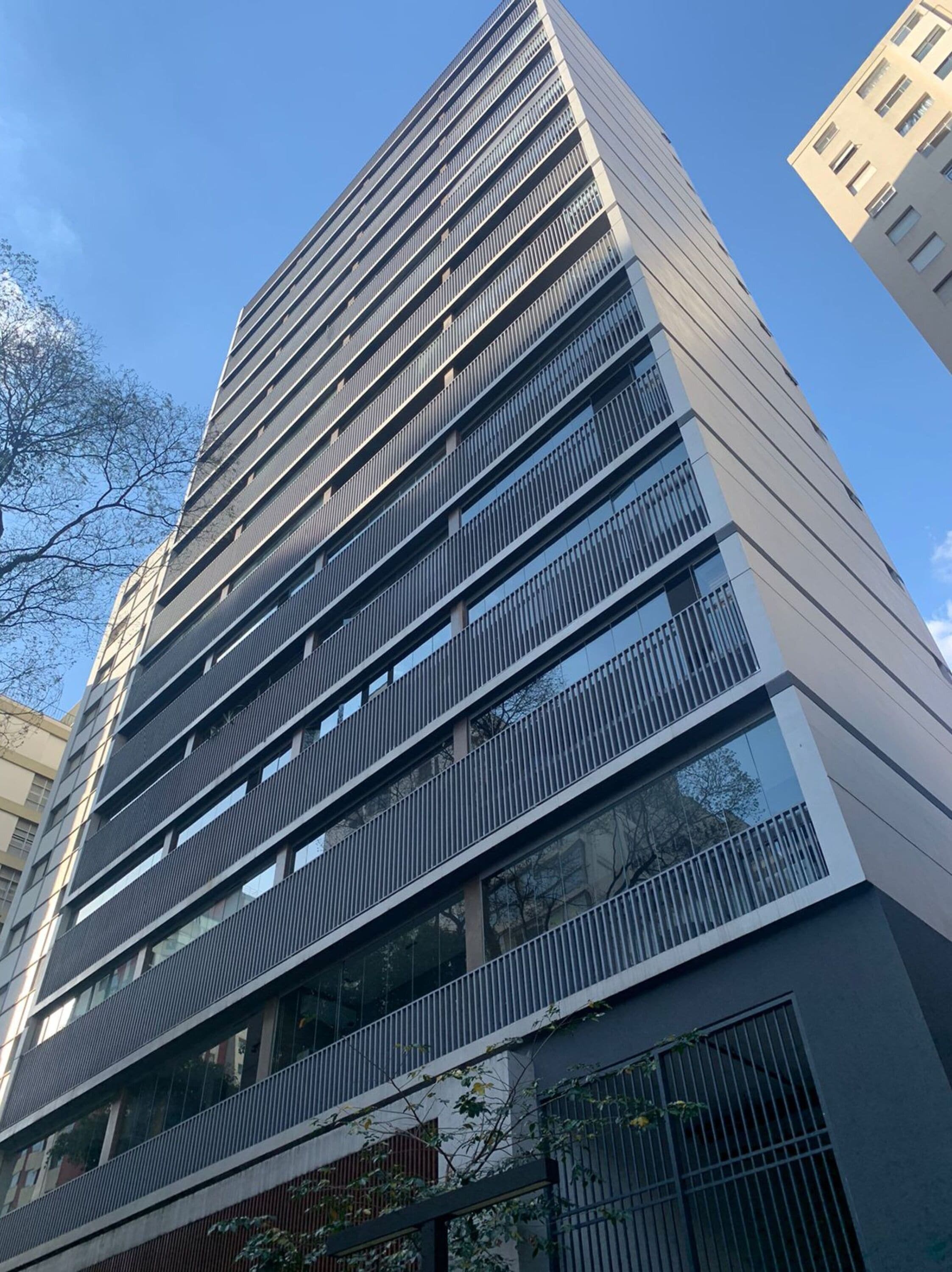 A modern high-rise building with multiple floors, large windows, and a mix of balconies and terraces.