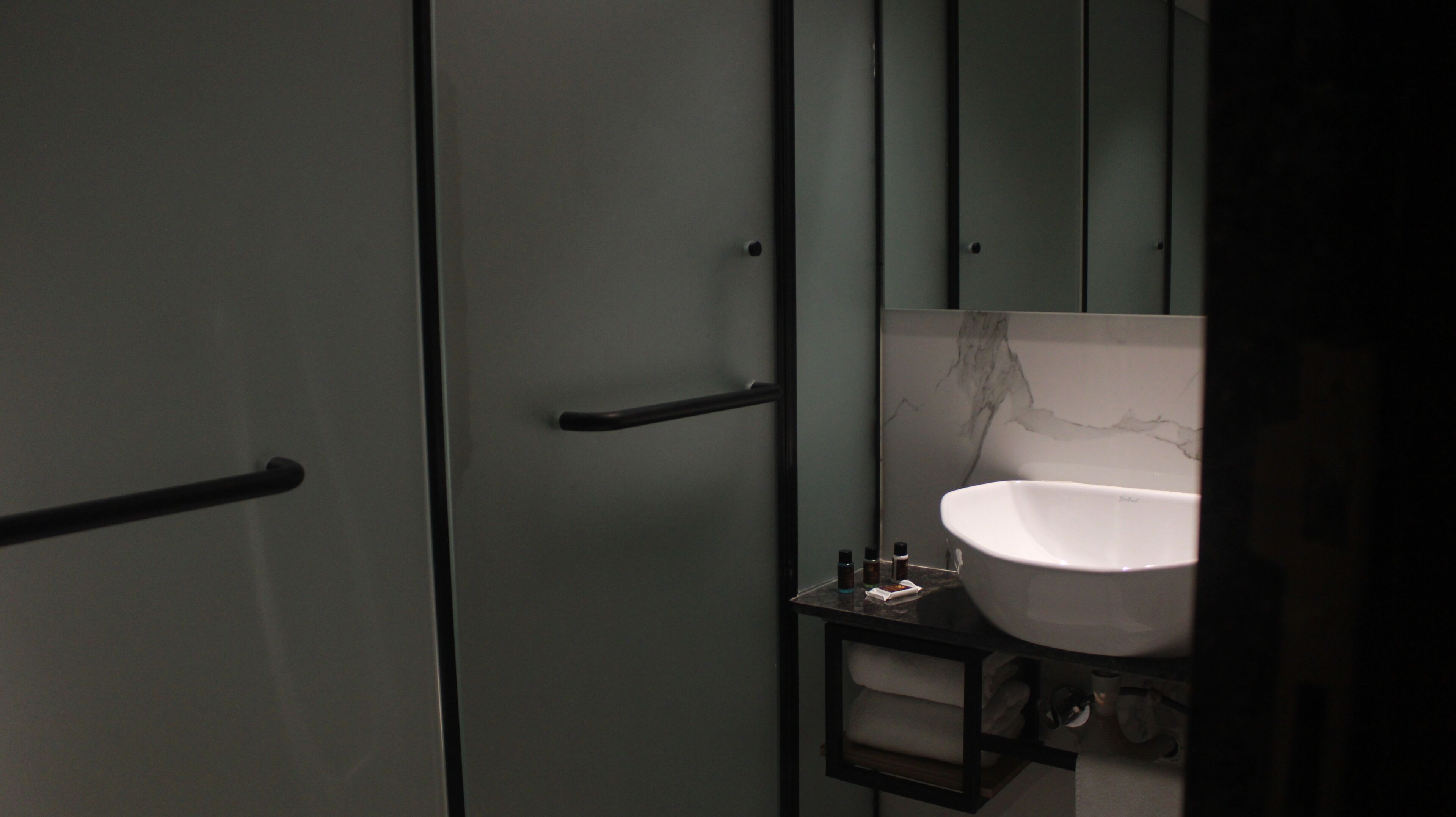 Un baño con lavamanos blanco, un espejo y un perchero para toallas.