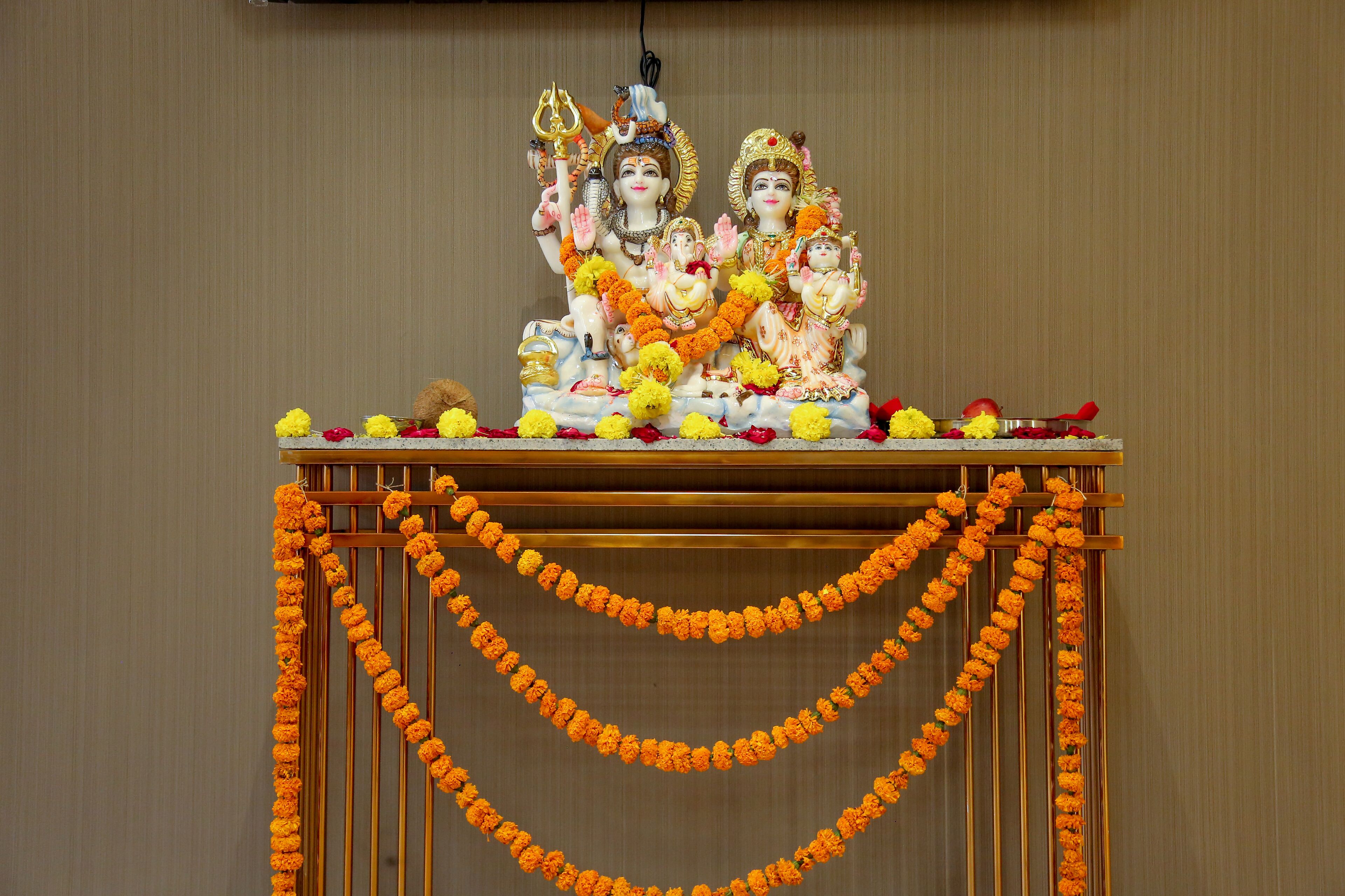 A statue of deities on a table with marigold garlands.
