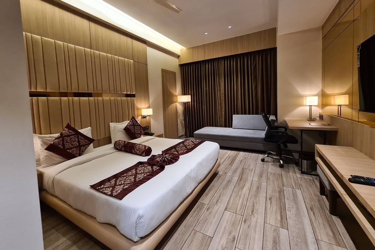 A hotel room with a large bed, a desk, a chair, and a ceiling fan.