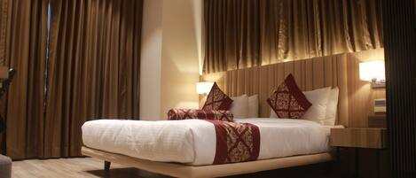 A hotel room with a large bed, wooden headboard, and a nightstand with a lamp.