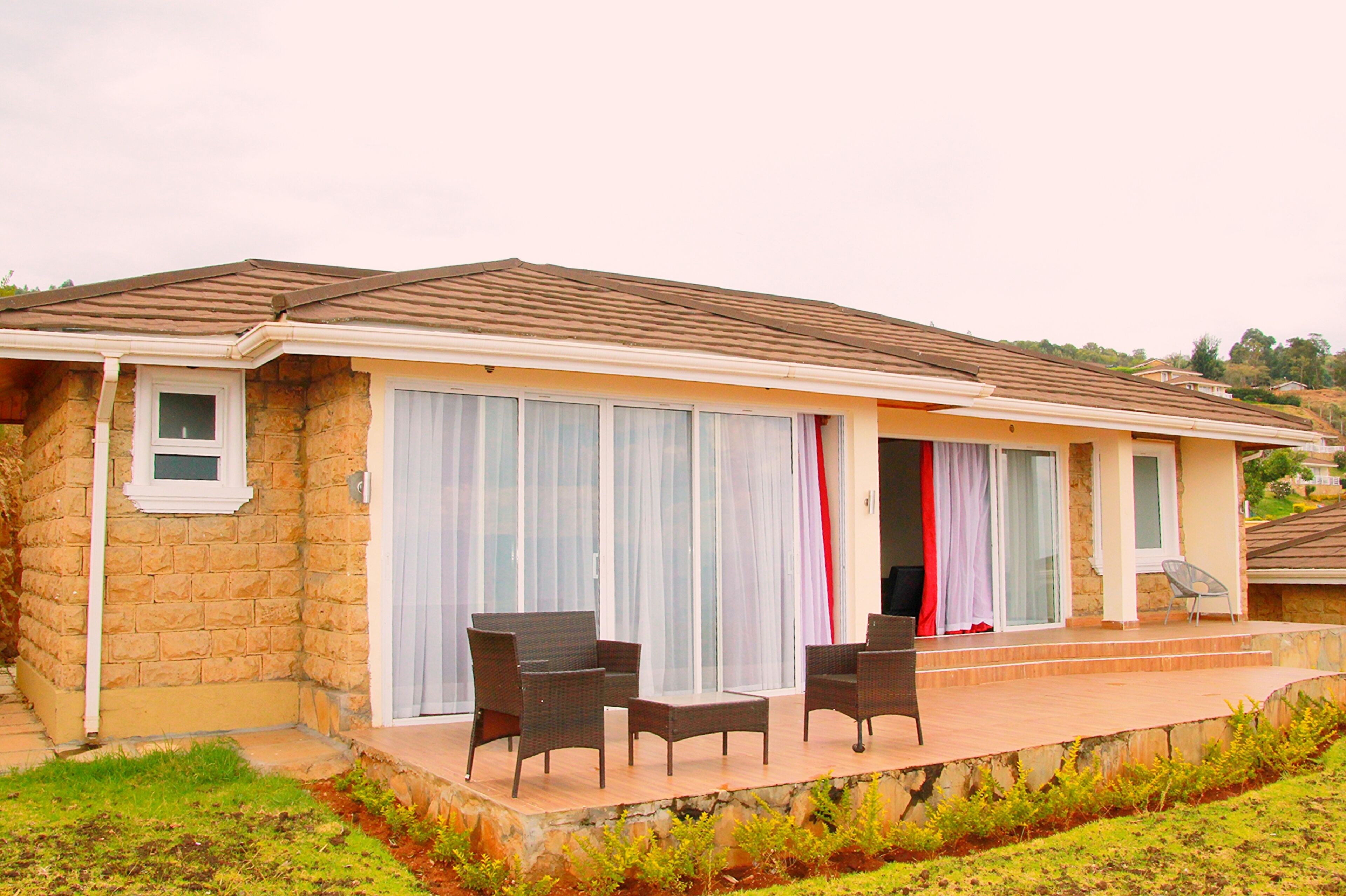 A stone house with a patio, two wicker chairs, and a small table.