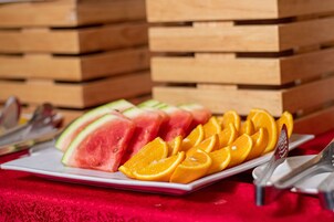 Un plato con sandía y gajos de naranja sobre un mantel rojo.