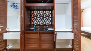 A walk-in closet with wooden louvered doors, a mirrored section, and a patterned divider.