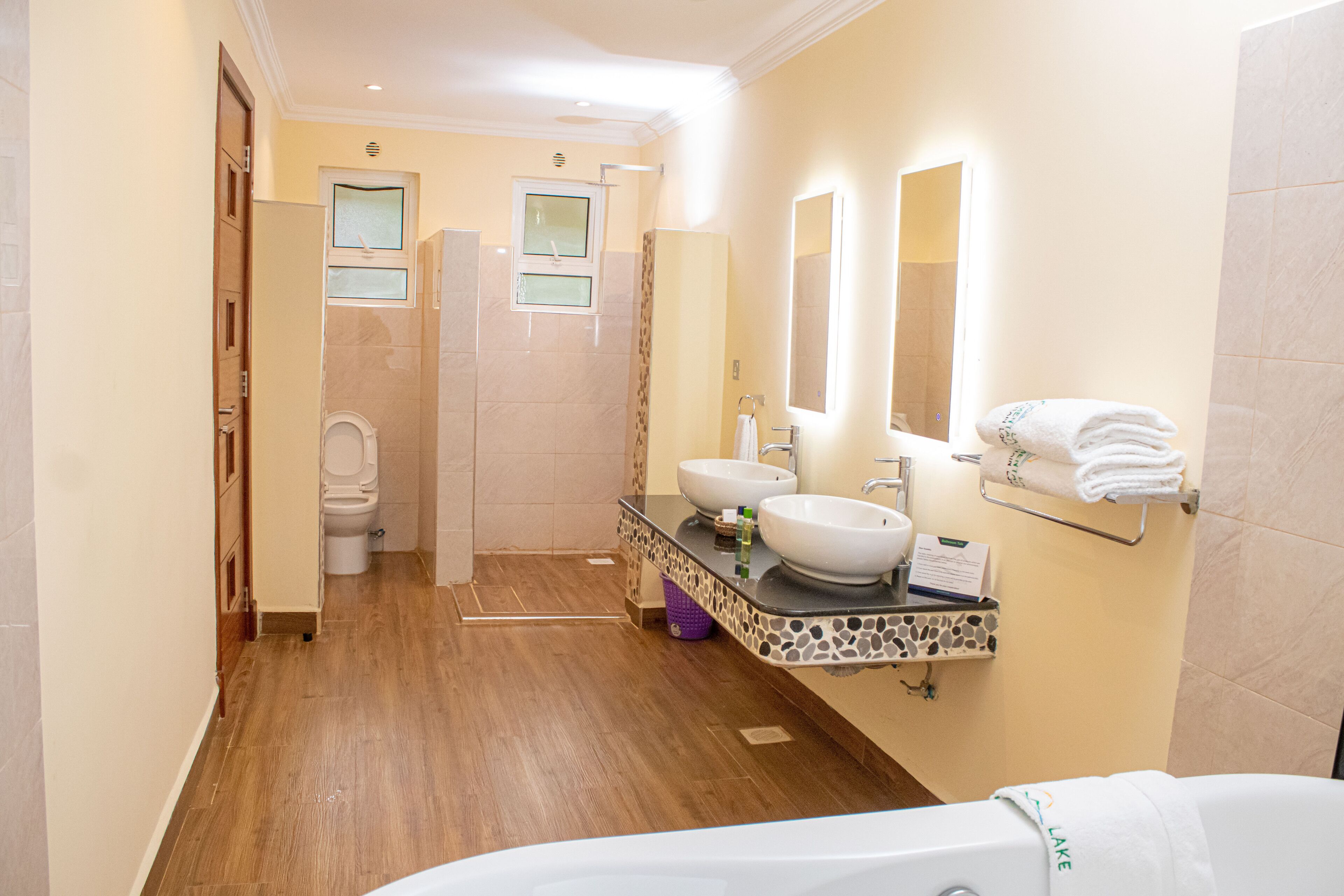 Ein modernes Badezimmer mit Holzboden, zwei Waschbecken, einer Badewanne und einer Duschkabine.