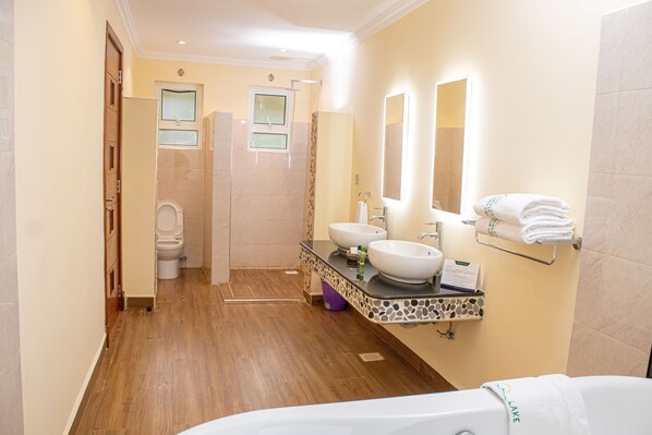 Un baño moderno con suelo de madera, dos lavamanos, una bañera y zona de ducha.