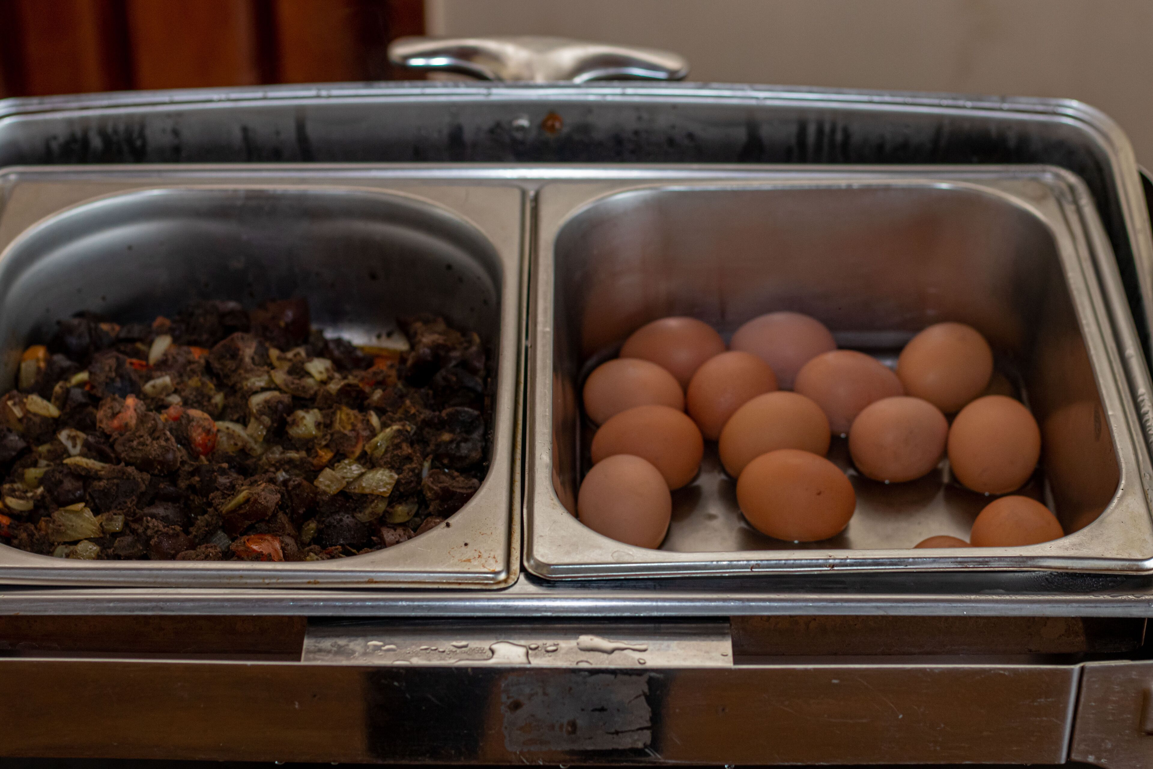 A buffet with two sections: one with cooked meat and vegetables, and another with eggs.