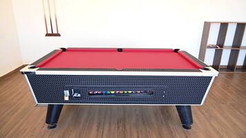 A pool table with a red felt top, black textured sides, and a built-in electronic scoreboard.