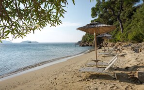 Di pantai, pasir putih, kursi berjemur, dan handuk pantai