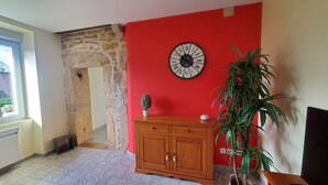 A room with a red wall, a wooden cabinet, a potted plant, and a wall clock. - The fountains (Laives)