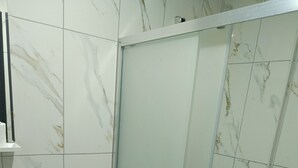 Ein Badezimmer mit Toilette, Waschbecken und einer Duschkabine aus Glas.