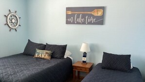A room with two beds, a wall clock, a welcome sign, and a paddle on the wall. - Spacious 4BD 3Bth townhouse on the peninsula! (Onamia)