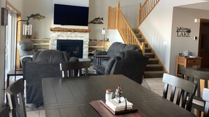 A living room with a fireplace, a dining table, and a staircase. - Spacious 4BD 3Bth townhouse on the peninsula! (Onamia)