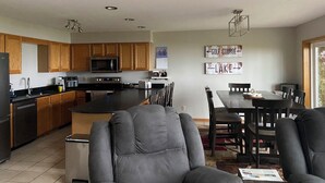A spacious kitchen with wooden cabinets, a central island, and modern appliances. There is a dining area with a table and chairs. - Spacious 4BD 3Bth townhouse on the peninsula! (Onamia)