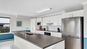 Eine moderne Küche mit weißen Schränken, einem Edelstahl-Kühlschrank und einer grauen Arbeitsplatte.