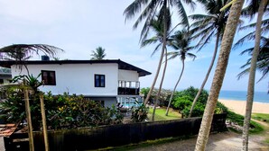 A white two-story house with a balcony, surrounded by palm trees and a view of the beach. - Beach villa KANDU near Hikkaduwa (Kumarakanda Dodanduwa)