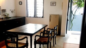 A dining area with a table and four chairs, a ceiling fan, a window with curtains, and a door leading outside. - Beach villa KANDU near Hikkaduwa (Kumarakanda Dodanduwa)