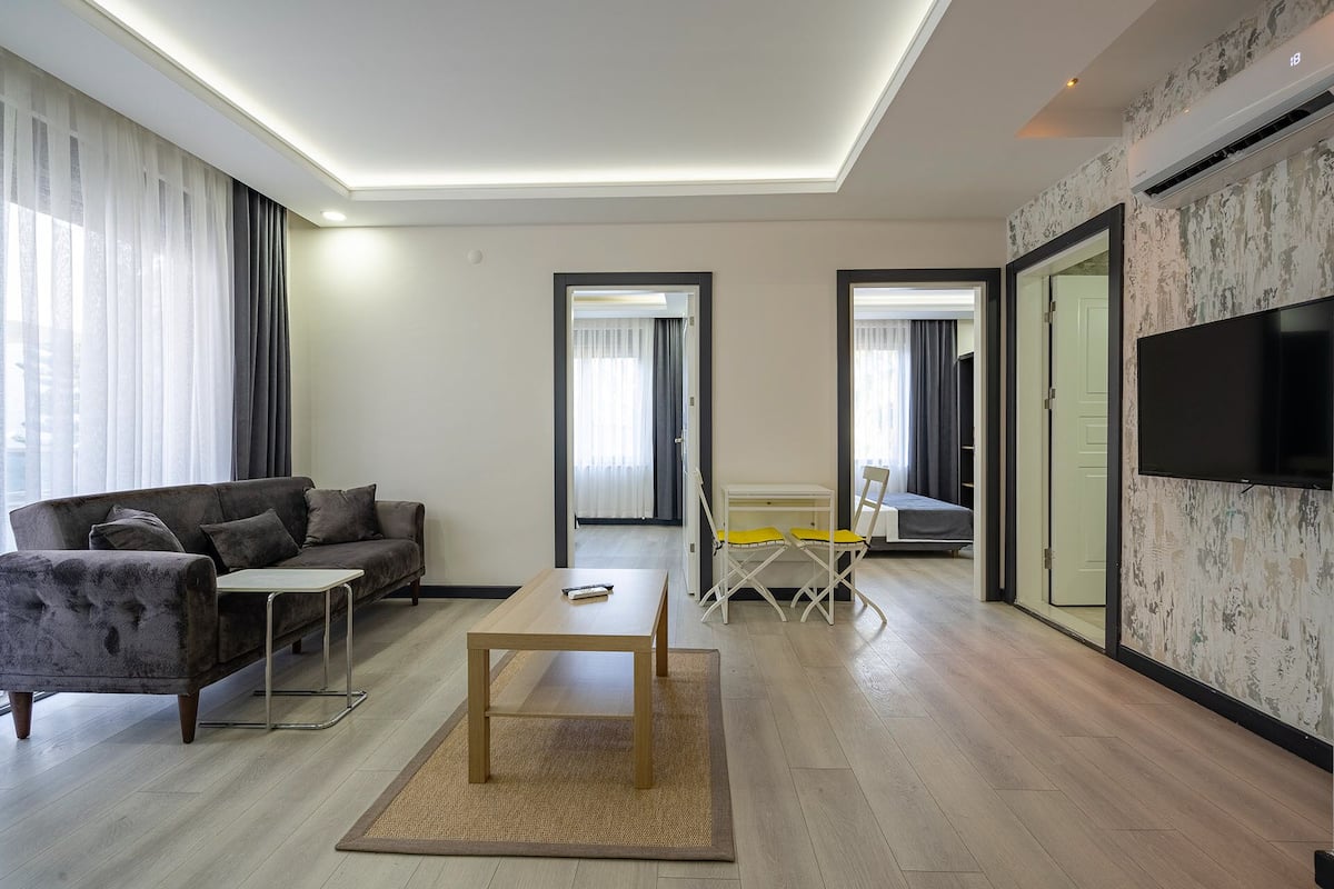 A modern living room with a sofa, a coffee table, and a TV mounted on the wall.