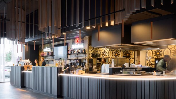 Un área de bar moderna con una barra curva, taburetes y una pared con diseño.