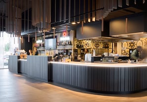 A modern bar area with a curved counter, bar stools, and a patterned wall. - Gr8 Hotel Breda (Breda)