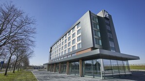 Un hotel moderno con fachada de vidrio, techo plano y un llamativo logo 'B' en la lateral.