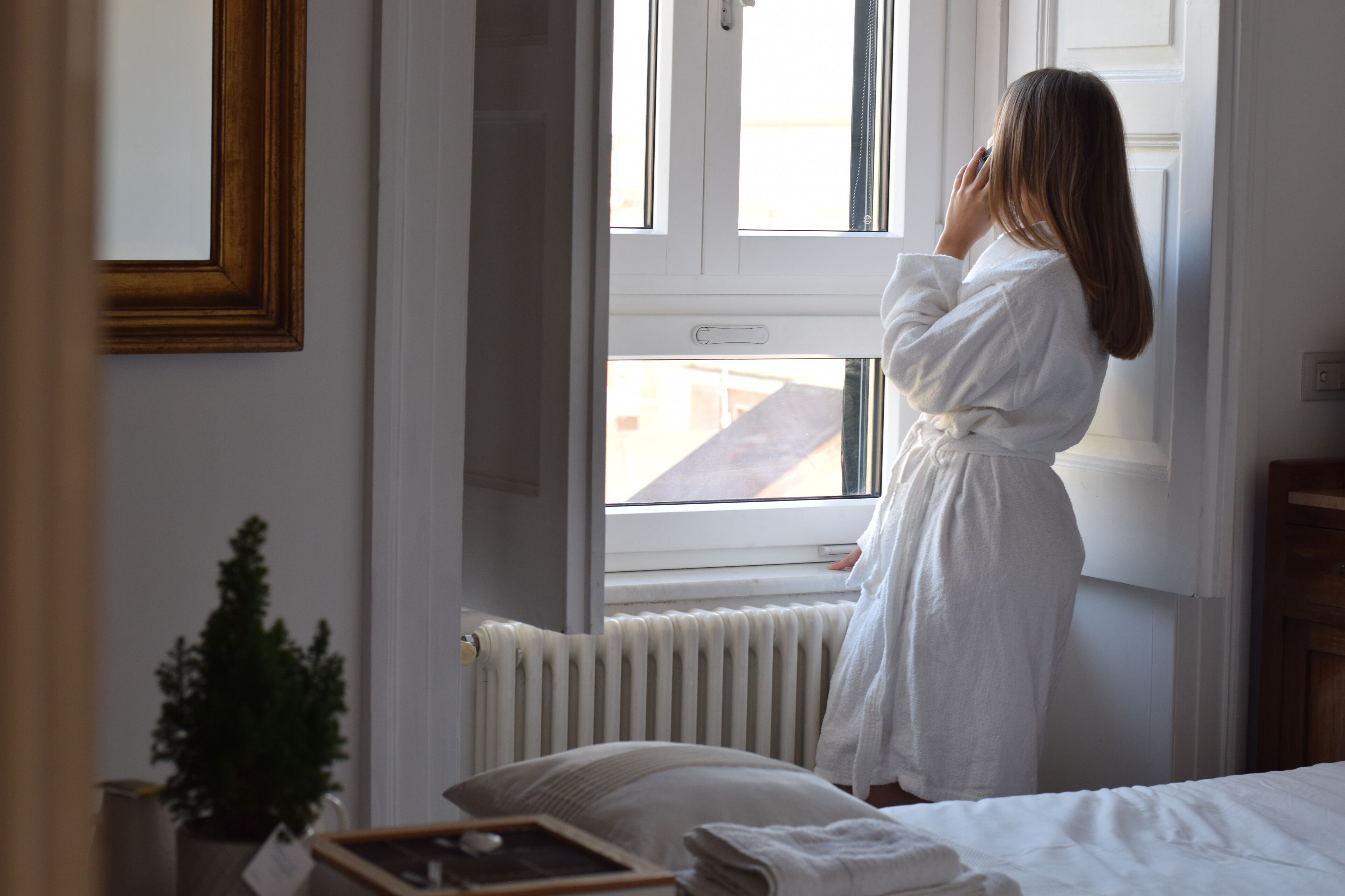 A room with a bed, a window, a radiator, and a framed picture on the wall.