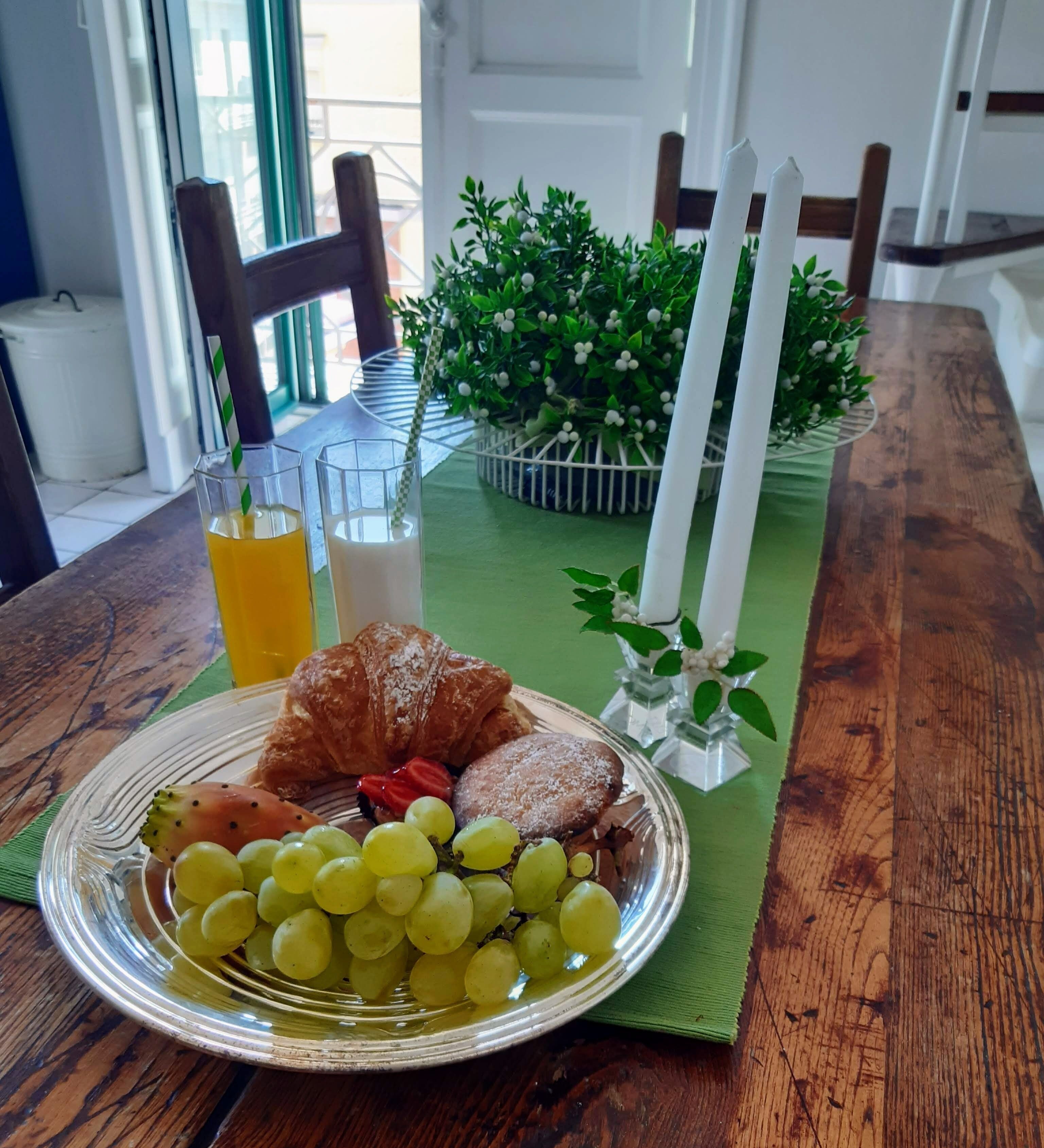 A breakfast setting with a plate of food, a glass of orange juice, a glass of milk, and a croissant on a wooden table.