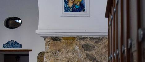 A stone wall with a potted plant and a framed artwork above it.