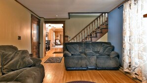 A living room with a sofa, a patterned rug, and a staircase leading to another room. - Chequamegon Haus - Comfortable and Charming walk to downtown Cable, WI (Cable)