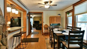 A kitchen with wooden cabinets, a bar area, and a dining table with chairs. - Chequamegon Haus - Comfortable and Charming walk to downtown Cable, WI (Cable)