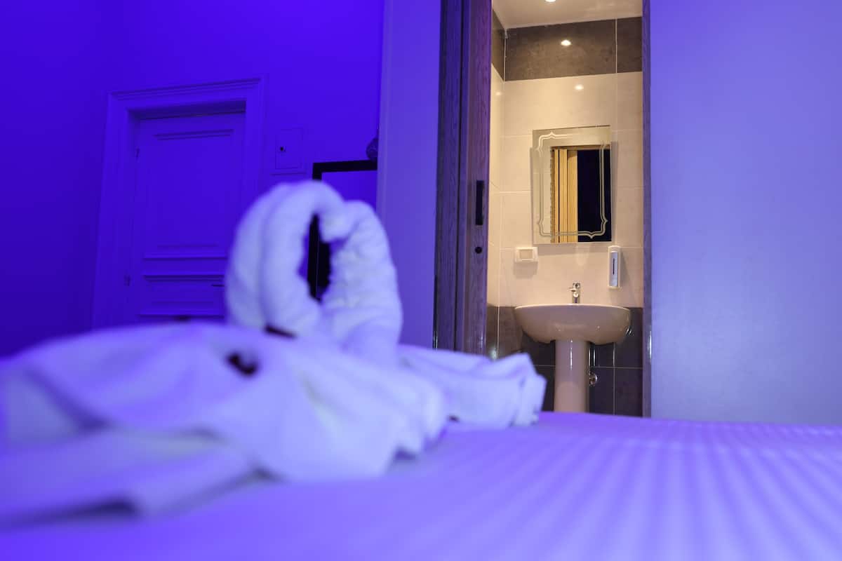 A hotel room with a bed, a bathroom visible through an open door, and a towel on the bed.
