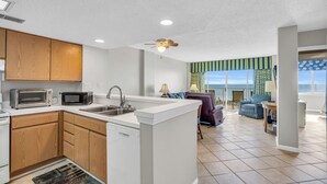 A modern kitchen with built-in appliances, a central island, and a dining area with a view. - Oceanfront Condo in Cherry Grove. Enjoy fun in the sun! Reduced Rates! (North Myrtle Beach)