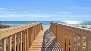 A wooden boardwalk leading to a beach with clear skies. - Oceanfront Condo in Cherry Grove. Enjoy fun in the sun! Reduced Rates! (North Myrtle Beach)