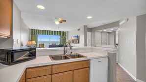 A modern kitchen with a microwave, sink, and dishwasher. - Oceanfront Condo in Cherry Grove. Enjoy fun in the sun! Reduced Rates! (North Myrtle Beach)