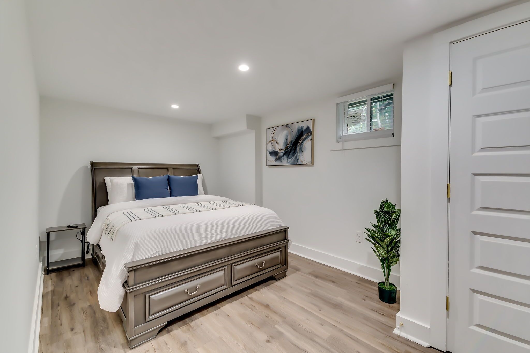 A bedroom with a bed, bedside tables, a window, and a door.