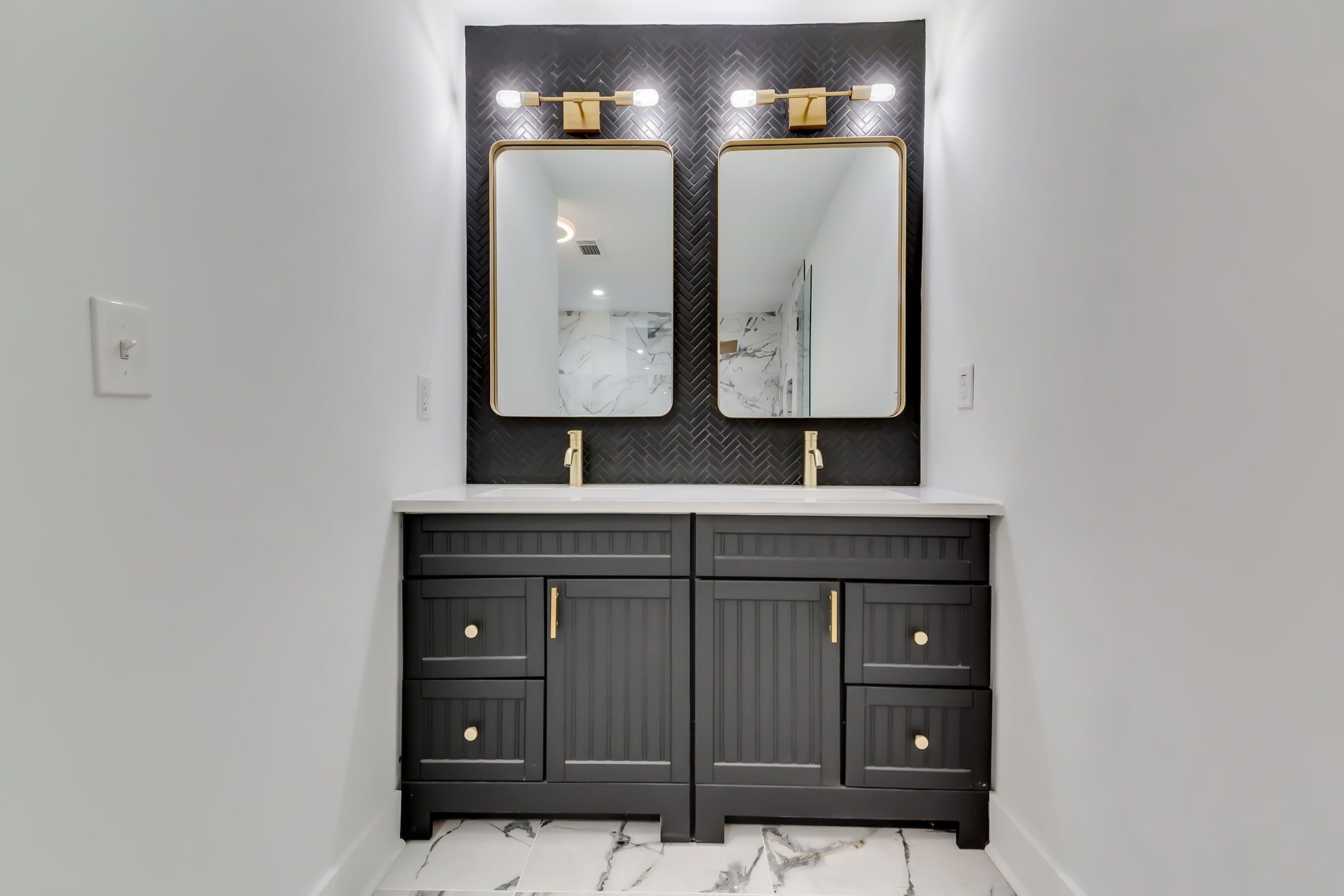 A bathroom with two mirrors, a white countertop, and a dark vanity with drawers.