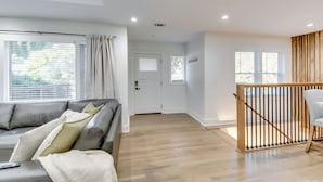 Uma sala de estar moderna com um sofá de couro cinzento, piso de madeira e escada com corrimão de madeira.
