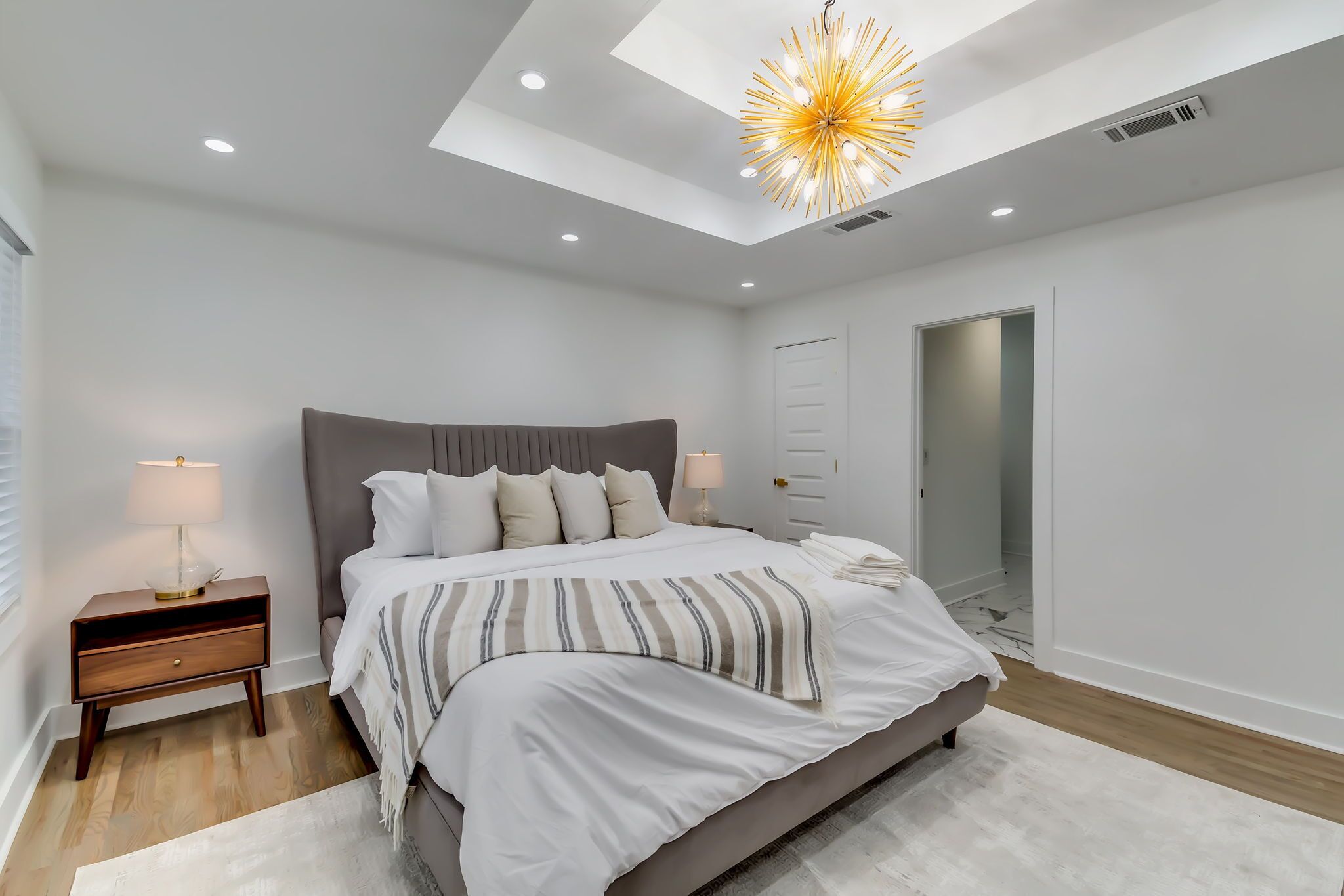 Un dormitorio moderno con una cama grande, lámparas de noche, una mesita de noche y un tragaluz.