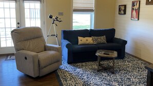 A living room with a beige armchair, a dark blue sofa, and a patterned rug.