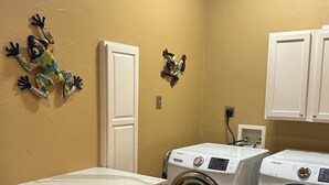 A laundry room with two washing machines, a sink, and dark wooden cabinets.