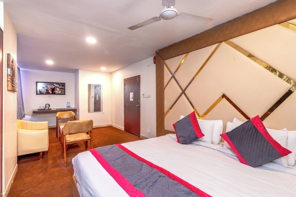 A hotel room with a bed, a desk, a chair, and a ceiling fan.