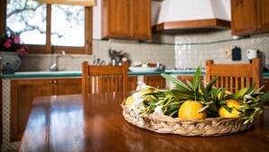 A kitchen with wooden cabinets, a dining table, and a basket of lemons and flowers.
