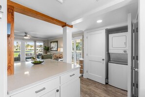A kitchen with a large island, white cabinetry, and a view to the outside. - Luxury 1.5BR Condo w/ Free Beach Service (Destin)