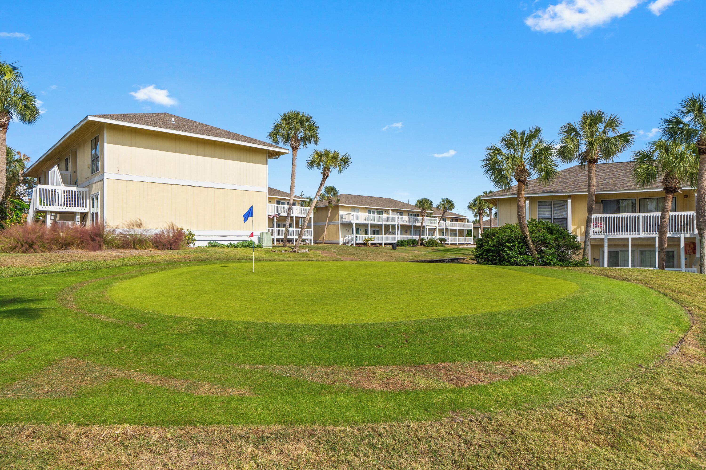 A golf course with a clubhouse and multiple-story buildings with balconies.