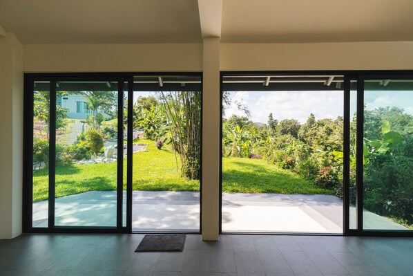 Un interior moderno con amplios puertas correderas de vidrio que dan a un exuberante jardín.