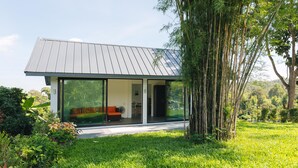 Et moderne hus med en stor glasdør, der fører til en stue med en sofa og et spisebord.